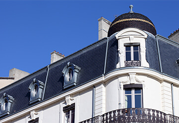 immeuble en pierre blanche avec balcon fenêtre toit et ciel bleu